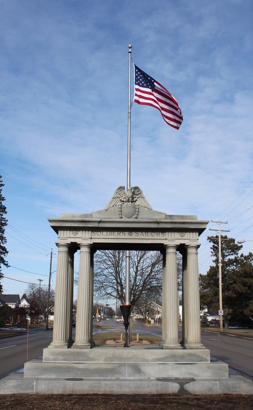 The Soldiers and Sailors monument with a waving American flag, offering shelter to the "Eternal Flame", which is still burning today.