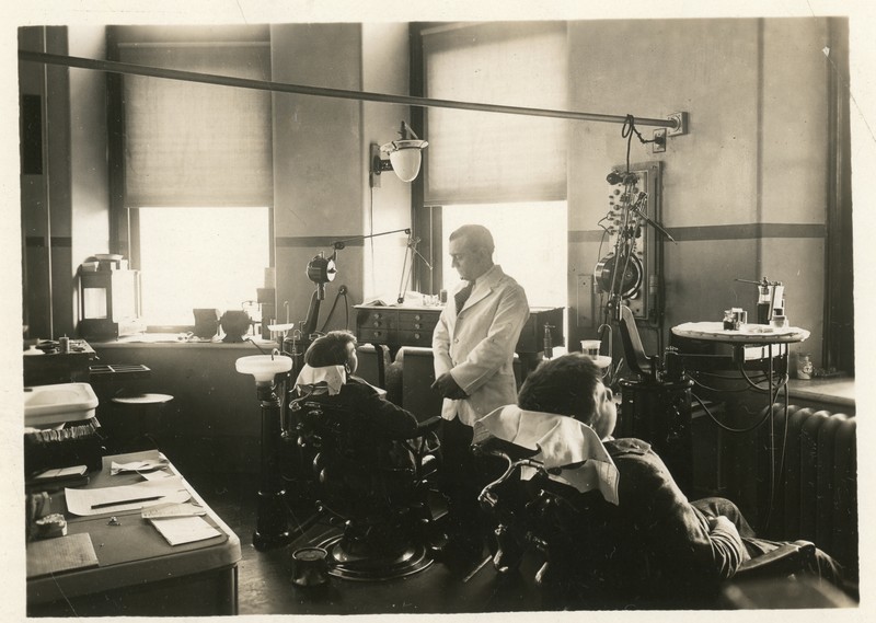 Photo of dentist standing in front of students seated in dental chairs of dental clinic's operating room.