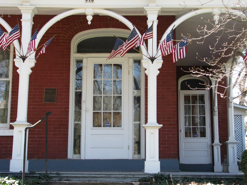 Flags decorate the wrap-around porch of the Mabel Hartzell Historical Home on days when the home is open for visitors