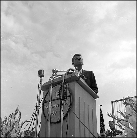 Kennedy stands at a podium at East Carolina College in front of approximately 12,000 people.