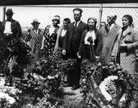 Family and friends stand by memorial wreaths for funerals of four men killed during the march