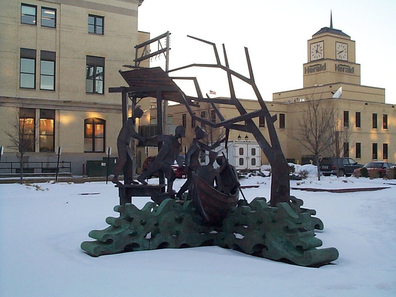 A memorial statue in Grand Forks with the rebuilt Grand Forks Herald building in the background