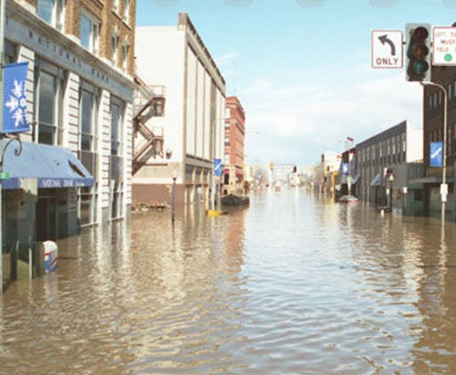 1997 photo of the intersection of 4th St and DeMers during the 1997 flood. The bank building can just been seen on the left background area. Courtesy of State Historical Society of North Dakota