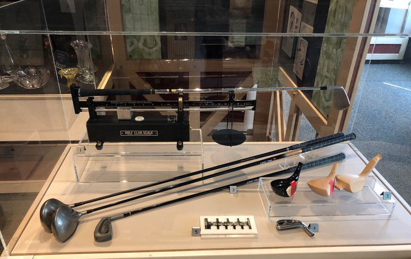 A golf club scale designed by Ralph Maltby of The GolfWorks, golf club's made by Dynacraft in their Pal Joey line, three blocks of persimmon showing the progress of making a golf club head, and other items supplied by GolfWorks.