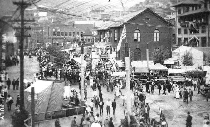 1909 photo of Bisbee during the Fourth of July festivities. The The Phelps Dodge Headquarters Building is seen in the center of the photo (side of building featured)