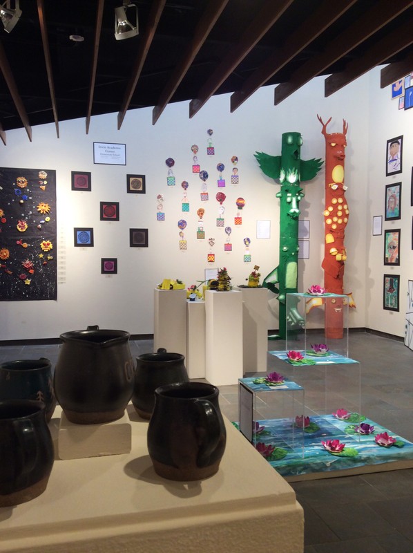 Rowe gallery, Keeping Watch: City of Creeks exhibit, 2018. Pottery is on display in the foreground and colorful artwork in the background.