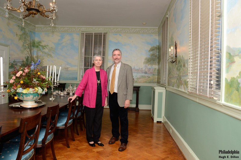 a couple stands in the mansion's Banquet Room that features a large, Dot Bunn mural depicting Philadelphia in the 19th century.