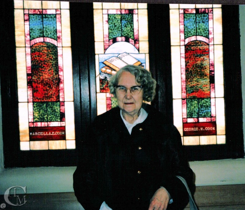 Church member, Jean Christianson stands in front of the stained glass window donated by Marcella and George Cook
