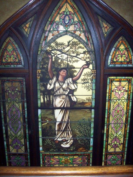 A stained glass on the wall behind the staircase that leads to the second floor.