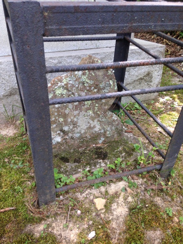 The original gravestone is caged to protect it from potential damage from visitors.