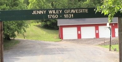 The grave is located down the trail on the left side of the fire station.