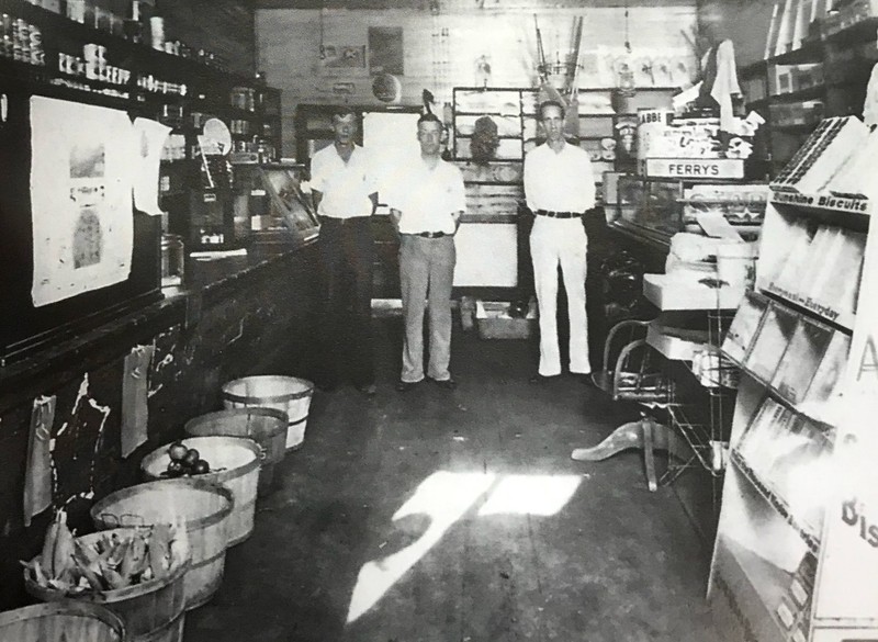 Inside of original Nicely's store. Left to right are Thad Cromptom, clerk and delivery man; A. C. Nicely, owner; and  Eugene Wells, a customer 