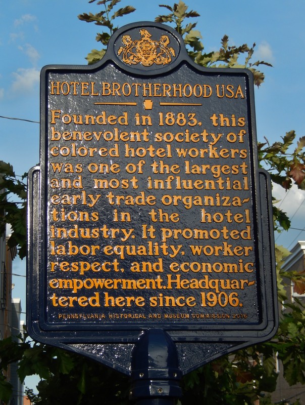 Metal sign with gold lettering, reading "Founded in 1883, this benevolent society of colored hotel workers was one of the largest and most influential early trade organizations in the hotel industry. It promoted labor equality, worker respect, and economic empowerment. Headquartered here since 1906."