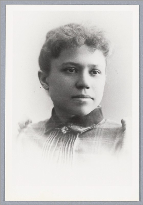 Black & White Photo. Portrait of woman with dark hair pull back. Plaid blouse with a dark collar.