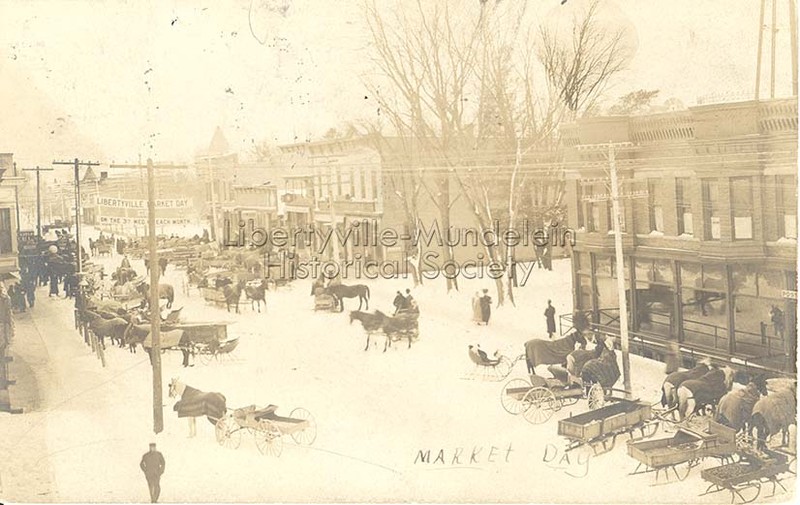 Market Day, circa 1908. Looking south on Milwaukee Avenue. On right, note street-level access to the basement of the Warren Heath building 