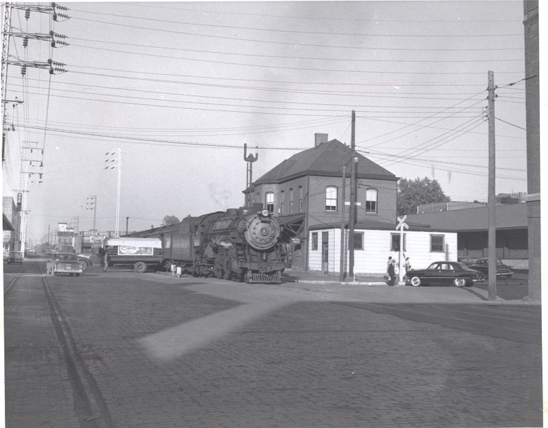 Passenger train pauses in Huntington, 1956. Seems as if a grandfather has come to town for a visit, while a Railway Express Agent unloads packages. Photo by Herbert H. Harwood, Jr., from the Bob Withers Collection. (2013).