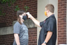 Faculty member testing a student's temperature