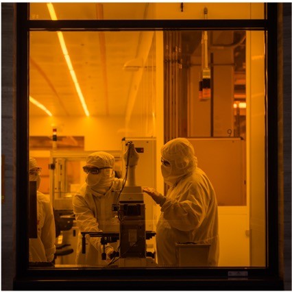 Color Photo. Individuals in cleanroom suits working 