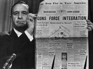 Orval Faubus holds up a local newspaper that interpretted Eisenhower's actions to enforce the decision of the Supreme Court and uphold integration as tyranny