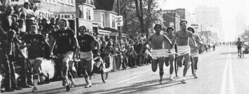Fraternity members race in chariots past Frank's, 1971