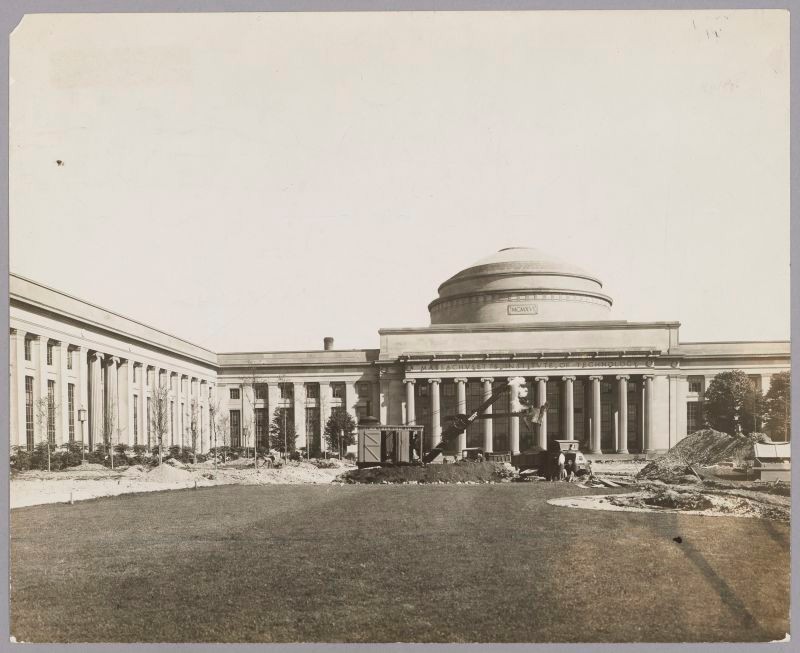 Black & white, domed building with columns across the facade. Steam shovels actively digging. Piles of dirt & gravel.