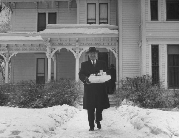 President Truman leaving the house on his way to a family event at Christmas time with presents in tow.