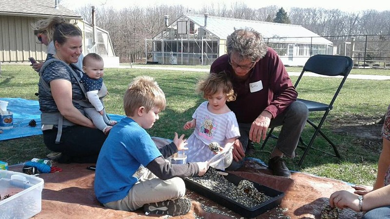 Volunteer helping graden adventures campers make pinecone bird feeders