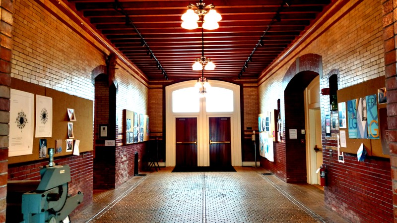 Visible examples of the wide, arched doorways of the stables. Along the walls are the distinctive yellow and red brick, and the drain-design of the floor can be more easily viewed on this scale. Photo taken by Ellen Tuttle.