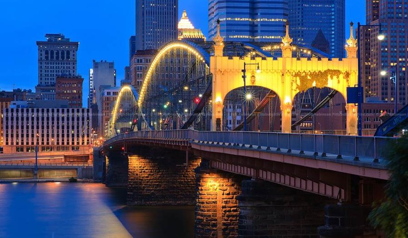 The bridge sporting its original color pattern and updated lighting with the Pittsburgh skyline in the background.  