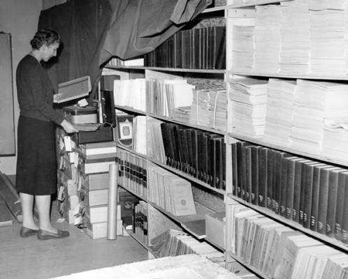 Head Librarian Ruth McBirney with a collection of periodicals in library storage at Boise Junior College, ca. 1961, before the Library Building was built.