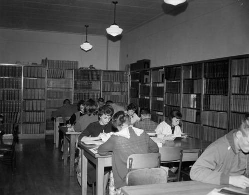 Students using the library to study. Notice the number of chairs per desk. By the early 1960s, the number of students was outgrowing the capacity of many of the buildings on campus. The Library was still located in the Administration building then.