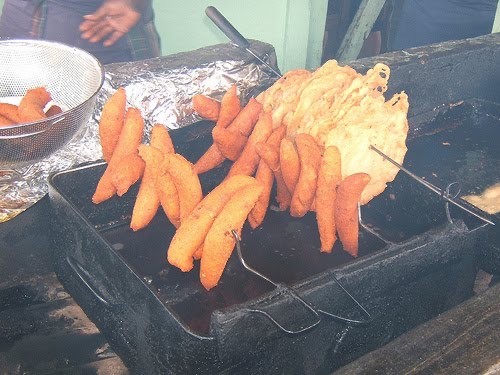 National fried foods being cooked outside and displayed for sale. In the picture, long 'alcapurrias' and rounded 'bacalaitos', two of the most famous fried foods of Puerto Rico, are on display.