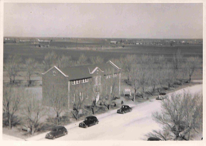 Photo of the Roosevelt County Museum. Four automobiles are parked on the street in front of the building.