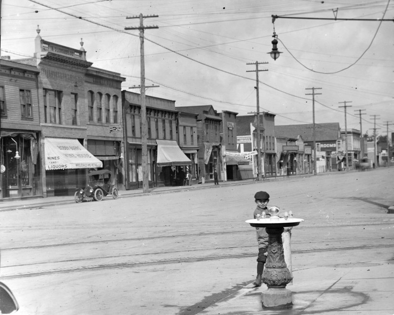 Photo of South Tacoma Way, circa 1913. A view of the west side of the 5200 block of South Union (now South Tacoma Way) looking north. A boy stands next to a sidewalk water fountain.