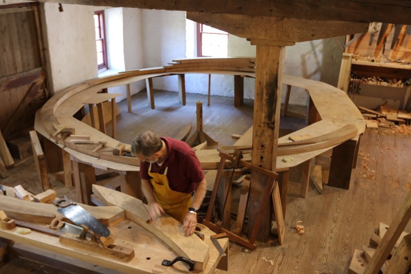 Image of a man at a workbench with a large circular layout table in the background.