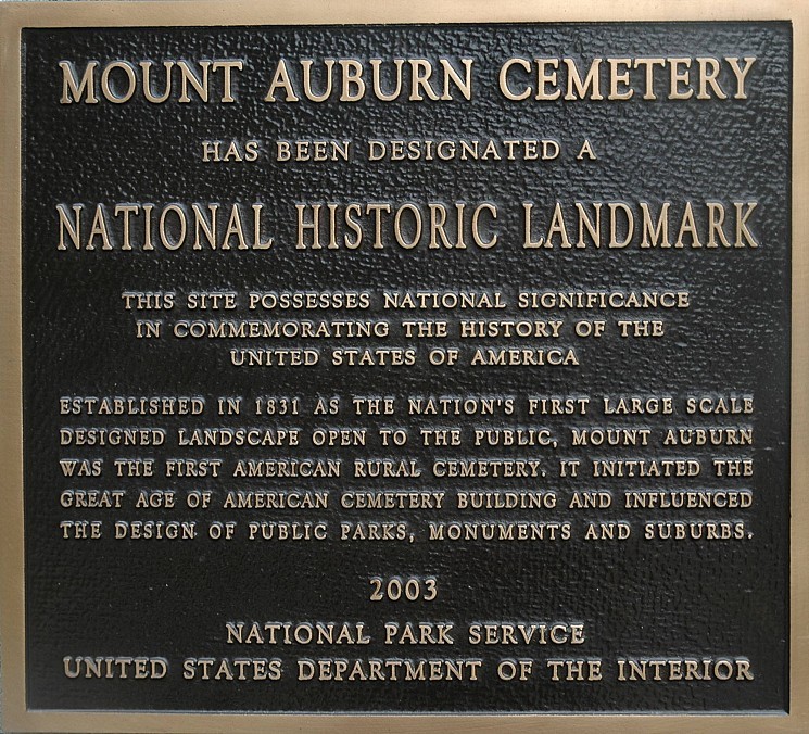 A plaque that reads, "Mount Auburn Cemetery has been designated a national historic landmark. This site possesses national significance in commemorating the history of the United States of America. Established in 1831 as the nation's first large scale designed landscape open to the public, Mount Auburn was the first American rural cemetery, it initiated the great age of American cemetery building and influenced the design of public parks, monuments and suburbs. 2003 National Park Service United States Department of the Interior."