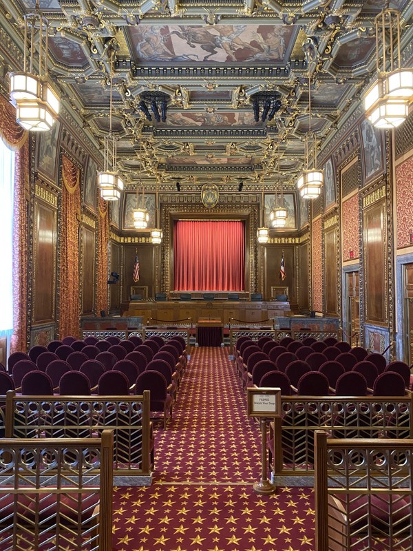 The courtroom of the Supreme Court of Ohio where the chief justice and six justices hear oral arguments. The decisions made by this court become governing law in Ohio. The original artwork in this room was painted by Rudolph Scheffler and depict the history of Ohio.