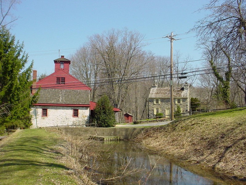 View from the headrace just before it passes under Cheney Road and enters the Grist Mill. A wooden trash rack to filter out debris can be seen at the opening of the pipe.