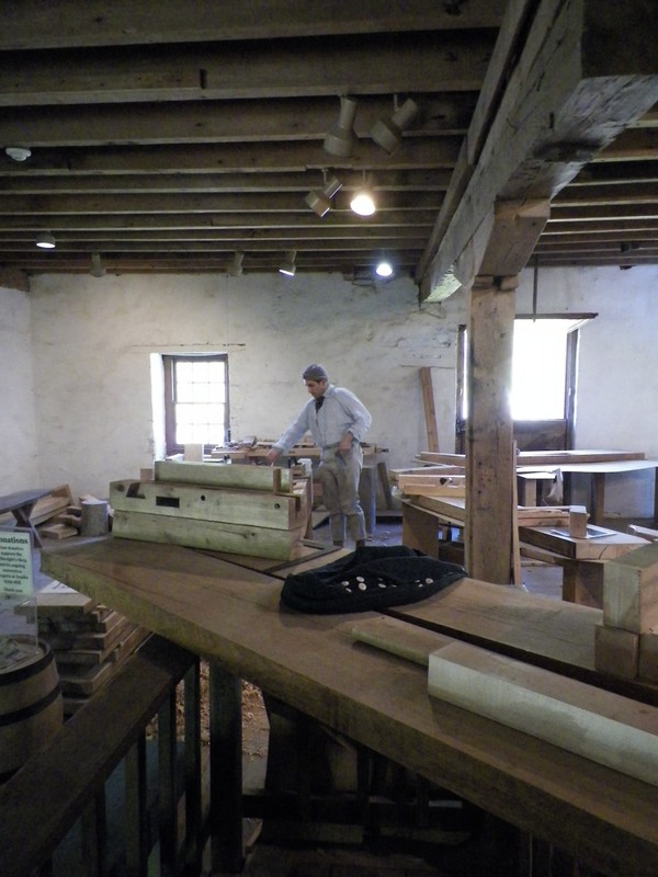 Image of man in period clothing working in the Millwright Shop.