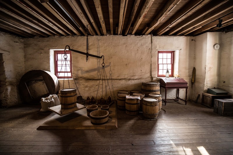 Image of a large balance scale with iron weights, wooden measures, and wooden barrels.