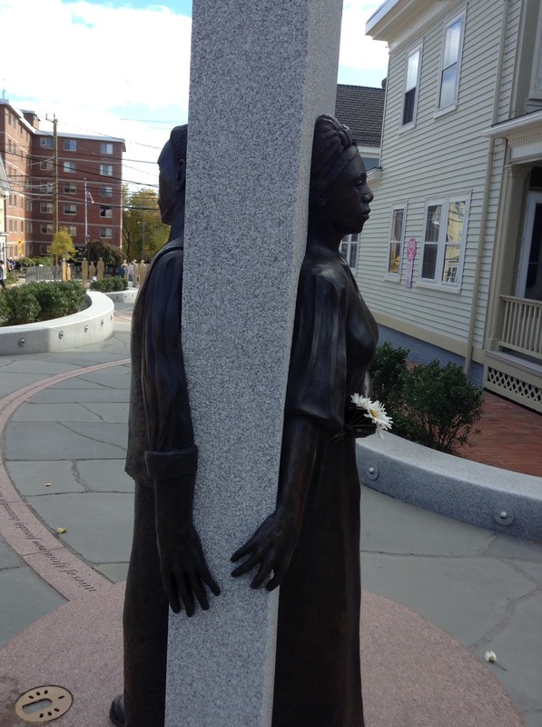 Sculpture of a man and a woman reaching around a slab towards the other, which expresses the numerous stages of separation, uncertainty, and perseverance that was imposed upon the Africans brought over as slaves.