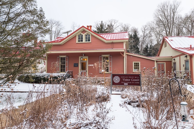 Wintertime exterior view of wood-sided building, painted red, with garden in front