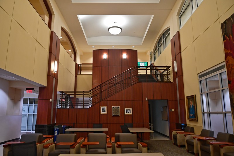 Two-story study lounge with tables, tablet arm chairs, and open staircase