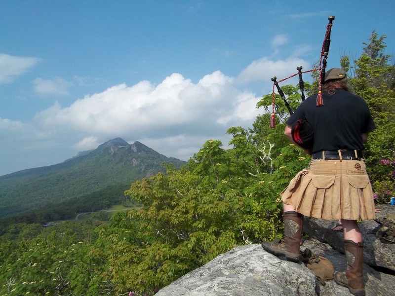 A piper plays from nearby Biscuit Rock above the MacRae Meadow campground.