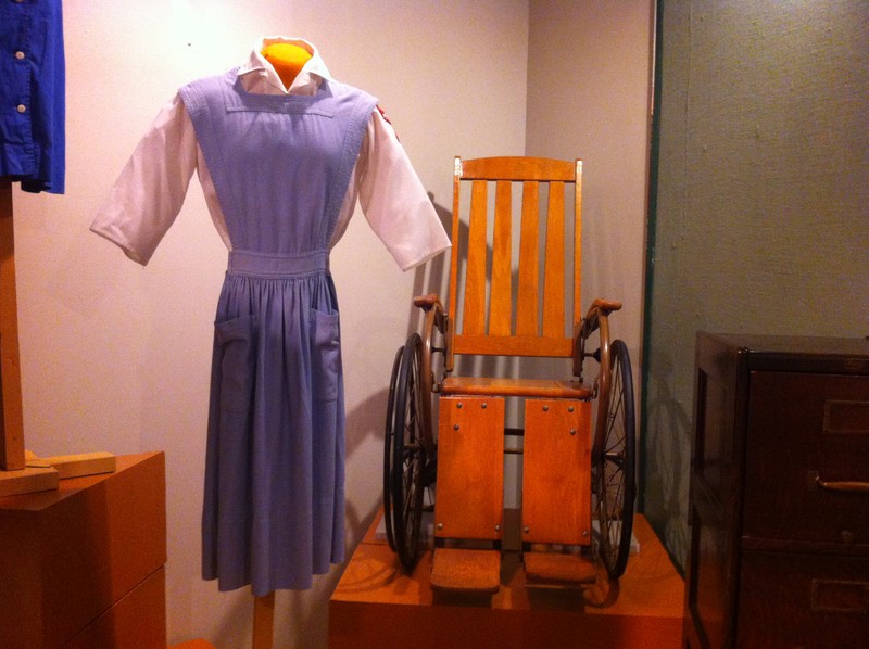 Red Cross Volunteer uniform worn by Jane Jensen at McCune-Brooks Hospital and wooden hospital wheelchair donated to Powers Museum in honor of Dr. Everett Powers when the museum opened. Powers was Chief of Staff when the hospital opened in 1929.