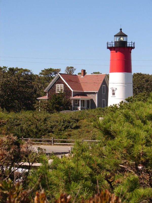 Looking north toward Nauset Light, showing its white light. The keeper's house (built in 1875 and moved to its current location in 1998) is to the immediate left of the lighthouse.