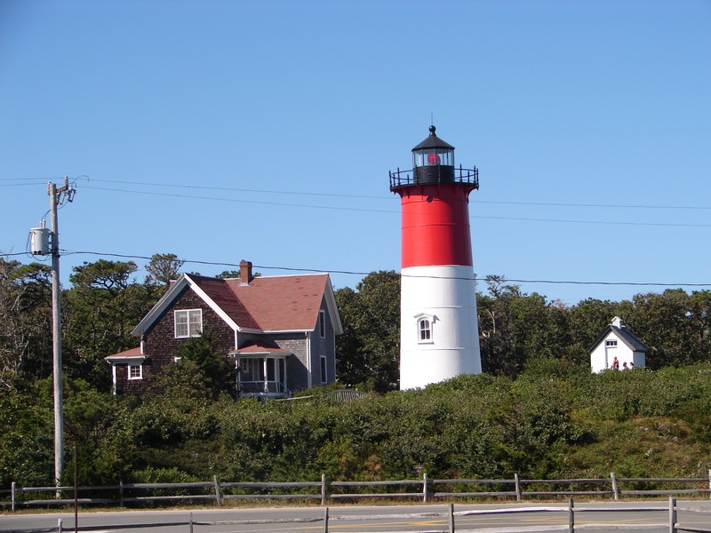 Nauset Light showing its red light (the light alternately flashes red and white every 5 seconds). The light's oil house (built in 1892, where fuel to illuminate the light was stored prior to the light's electrification) is visible to the right.