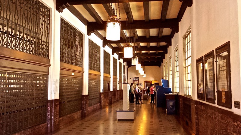 The large lobby of the post office with lantern light fixtures and marble tiled floor.