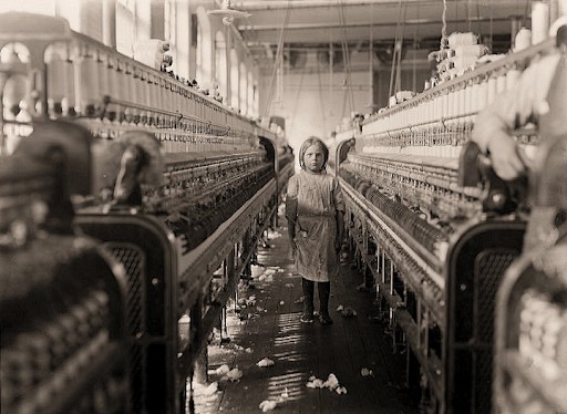 A young girl stands among machines - Hines noticed she was steadily working despite the manager claiming she "just happened in".