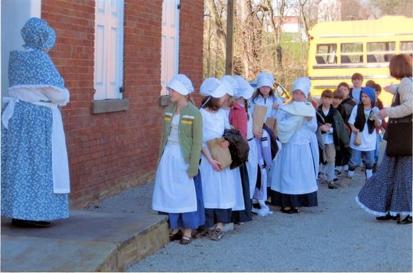 Students entering the school house dressed in period clothing for the day class.